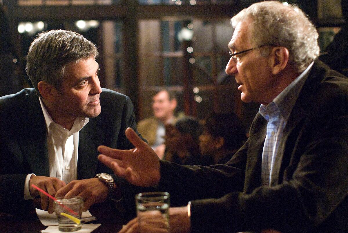 Two businessmen speak in a bar.