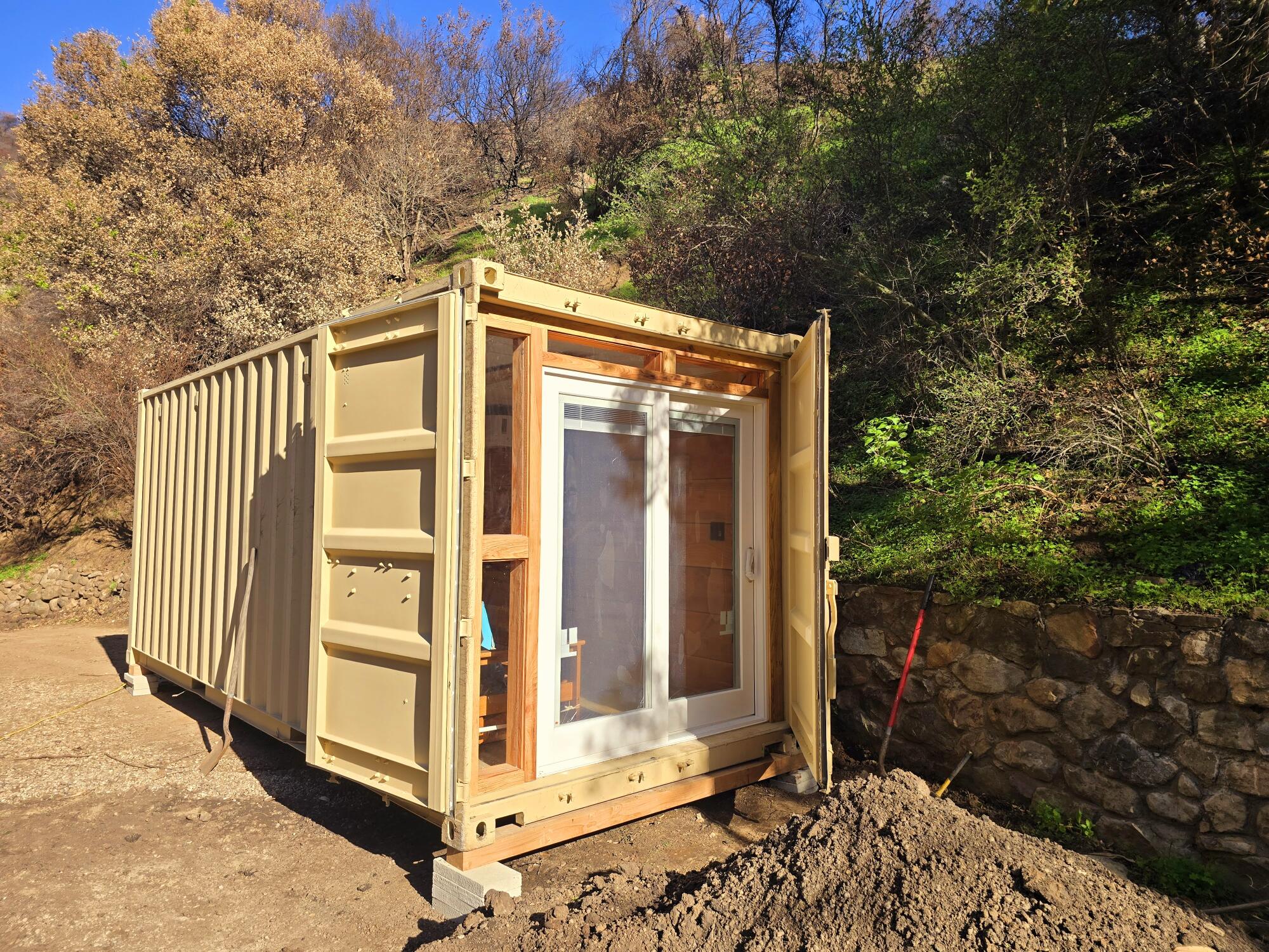 A converted shipping container has been fitted with a sliding glass door at one end.