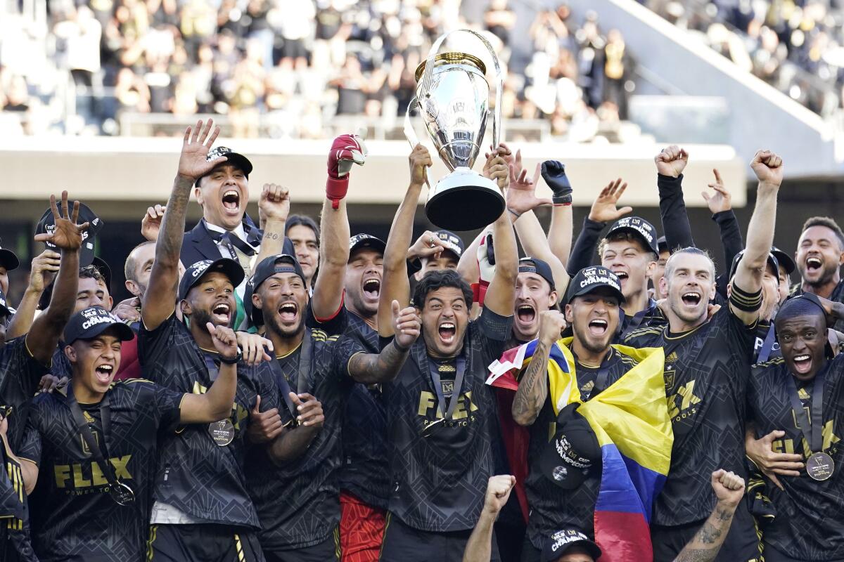 Los Angeles FC's Carlos Vela hoists the trophy alongside teammates after defeating.