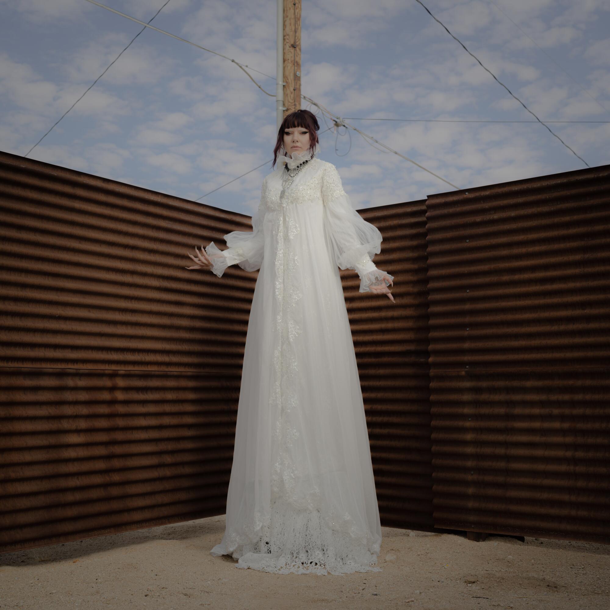 King Mala standing in a very long ornate white dress