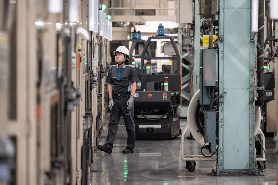 Factory worker standing in an aisle between industrial machinery.