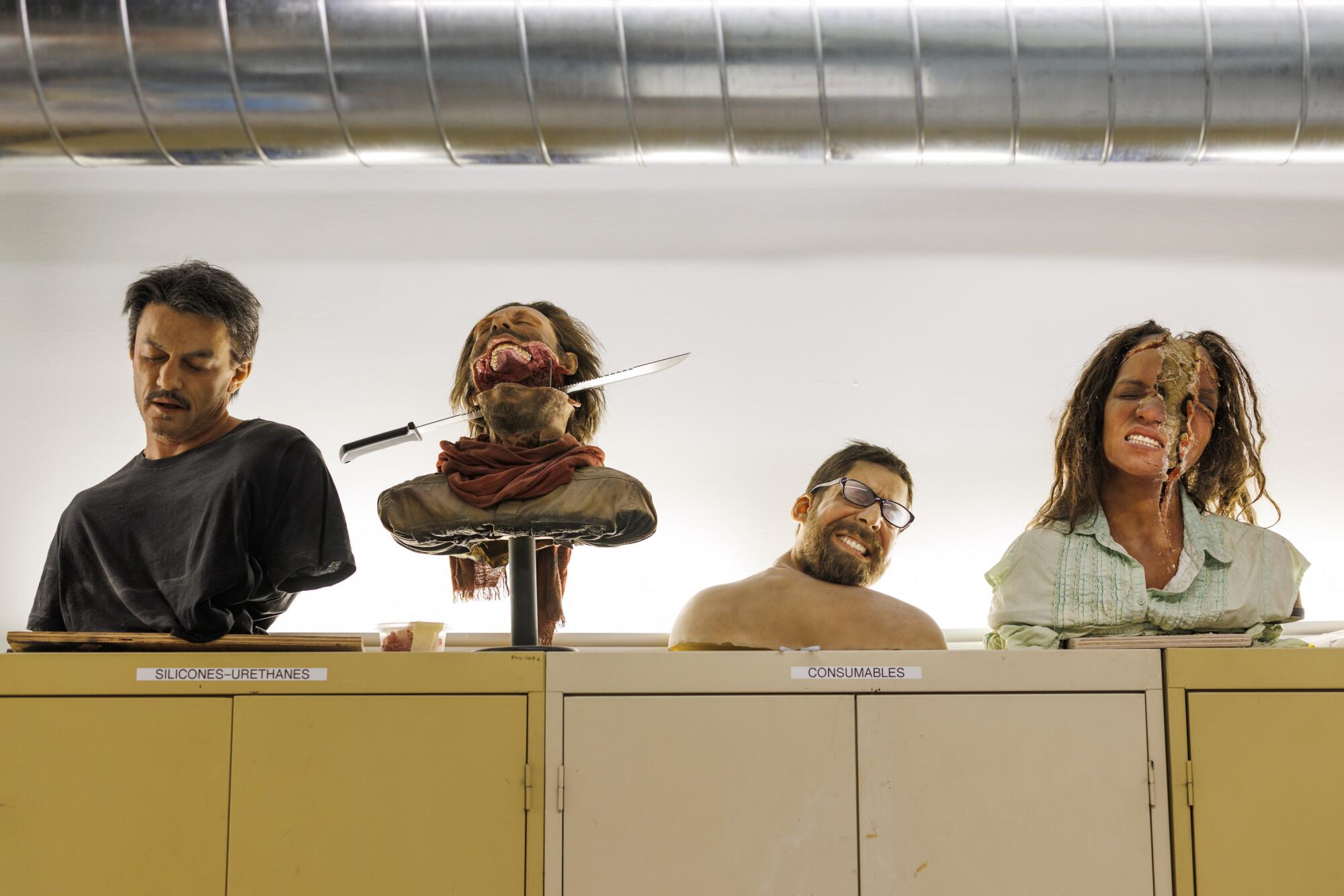 Several prosthetic heads sit on a shelf in a design studio.