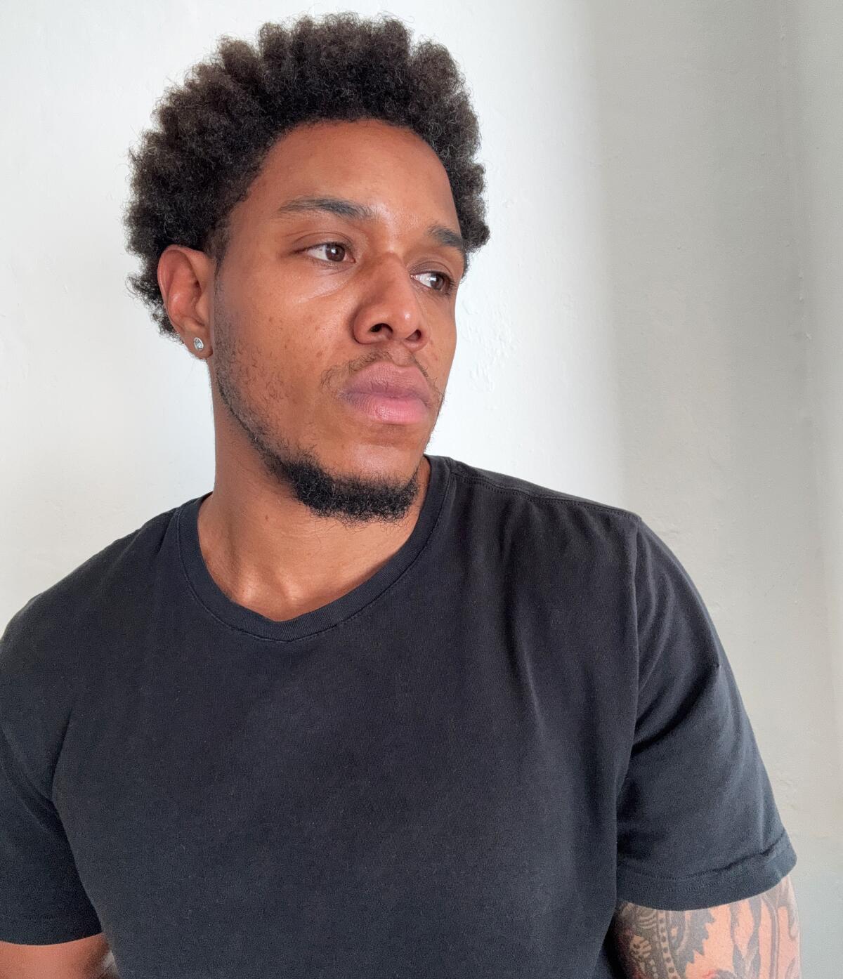 Noah Humes, in a black T-shirt, looks to the side.
