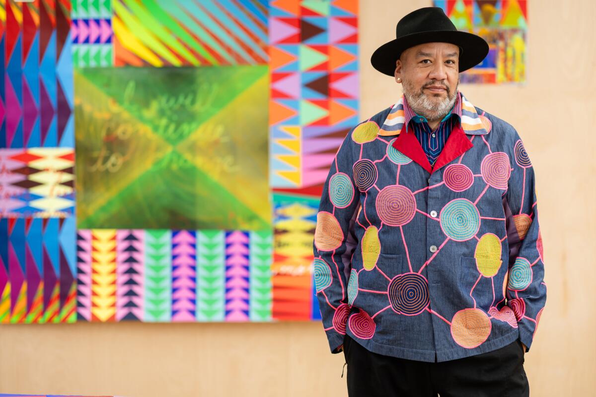 Artist Jeffrey Gibson stands in front of one of his virbantly hued artworks.