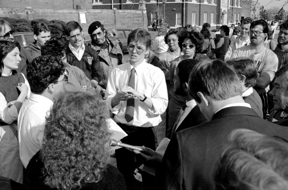 A man wearing a tie is surrounded by a crowd