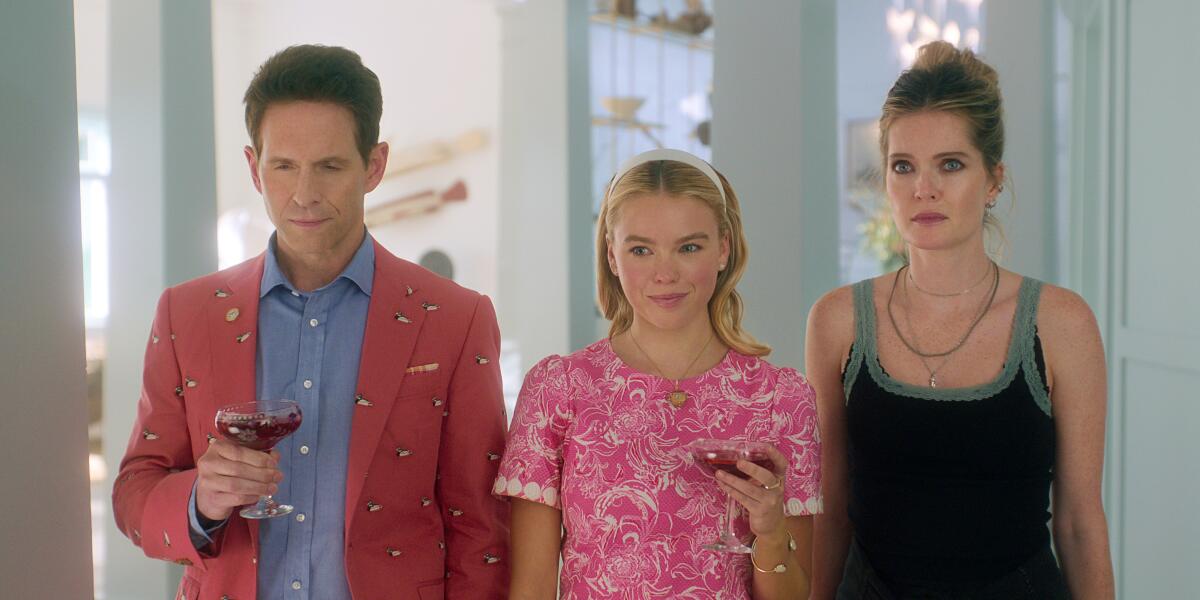Glenn Howerton, Milly Alcock and Meghann Fahy stand shoulder to shoulder holding cocktail glasses.