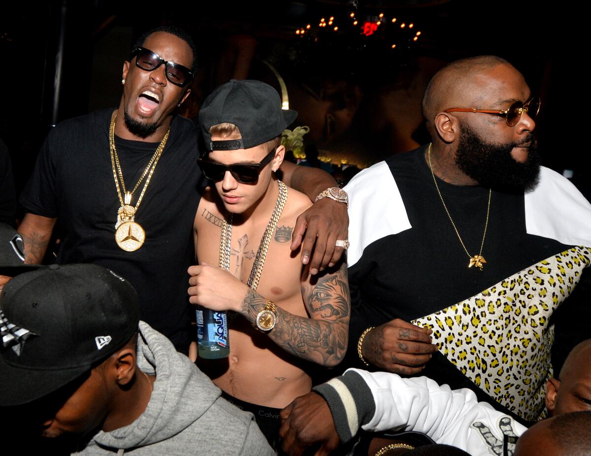 Sean Combs hollers with his arm around a shirtless Justin Bieber next to Rick Ross