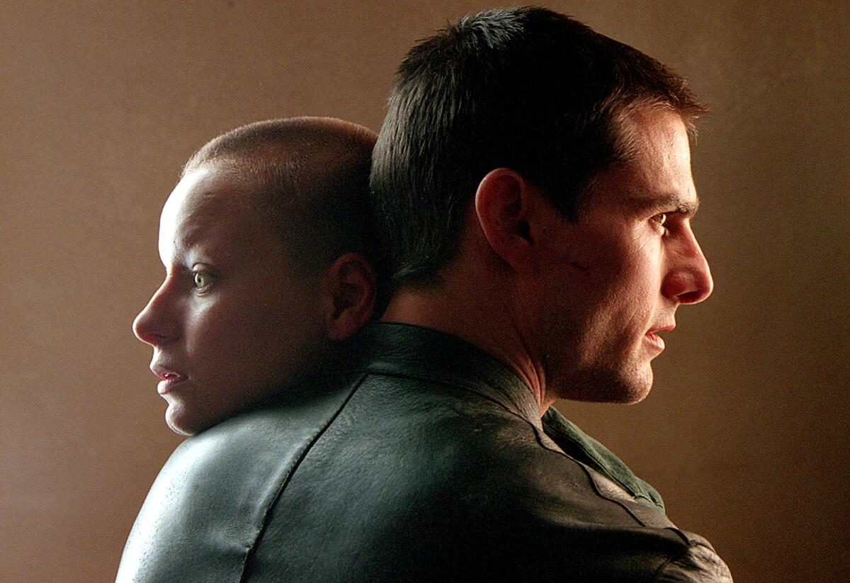 A bald woman and a man look away from each other.