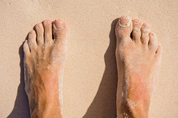 A picture of feet covered in sand at the back
