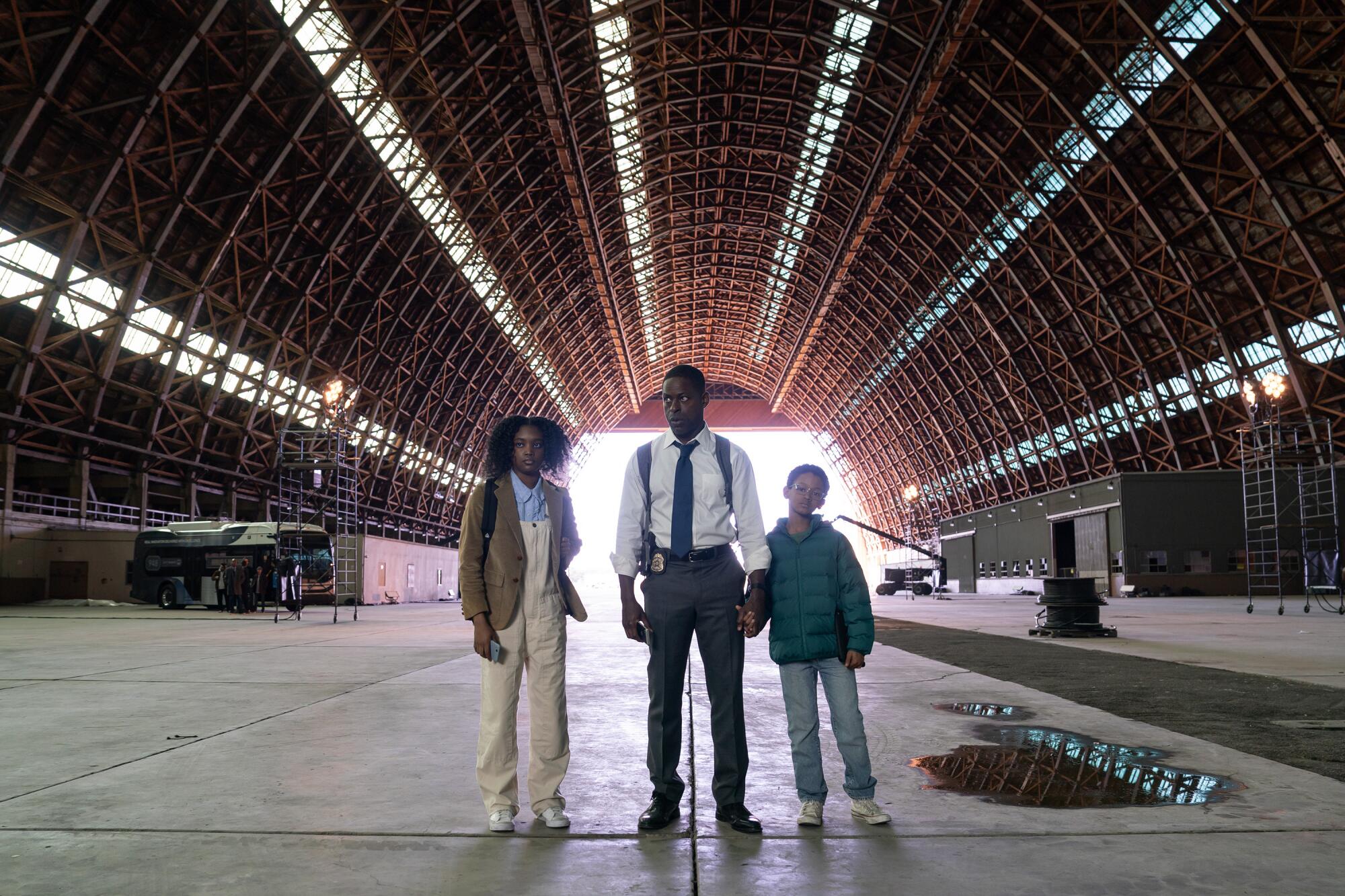 A young woman, a man and a young boy stand at the entrance to a bunker
