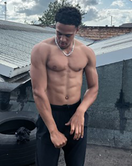 Shirtless man with muscular physique wearing black pants.