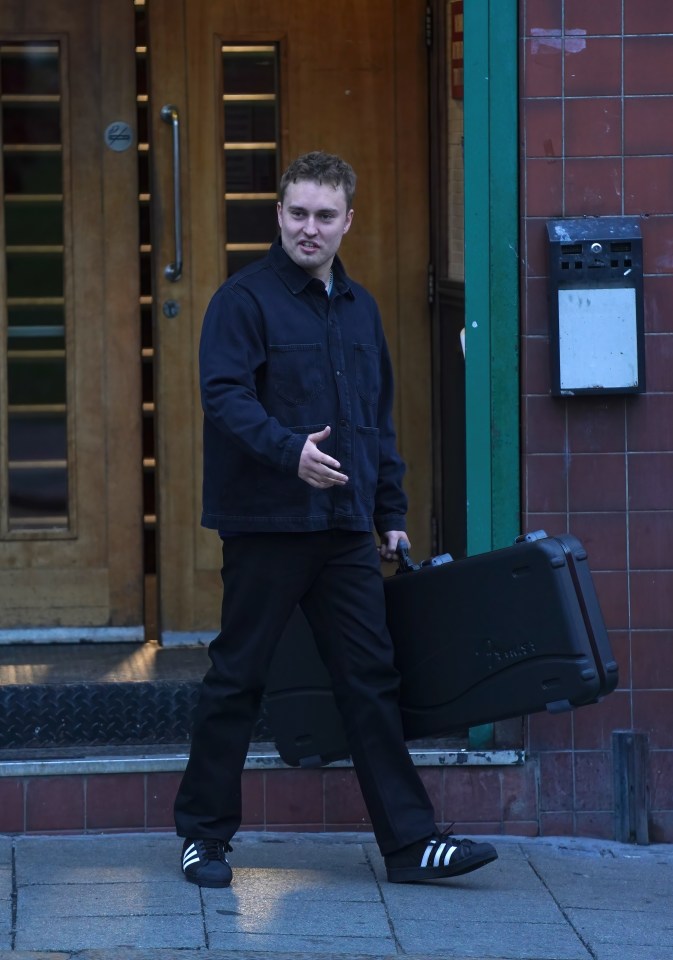 Sam Fender carrying a guitar case while filming an Adidas commercial.
