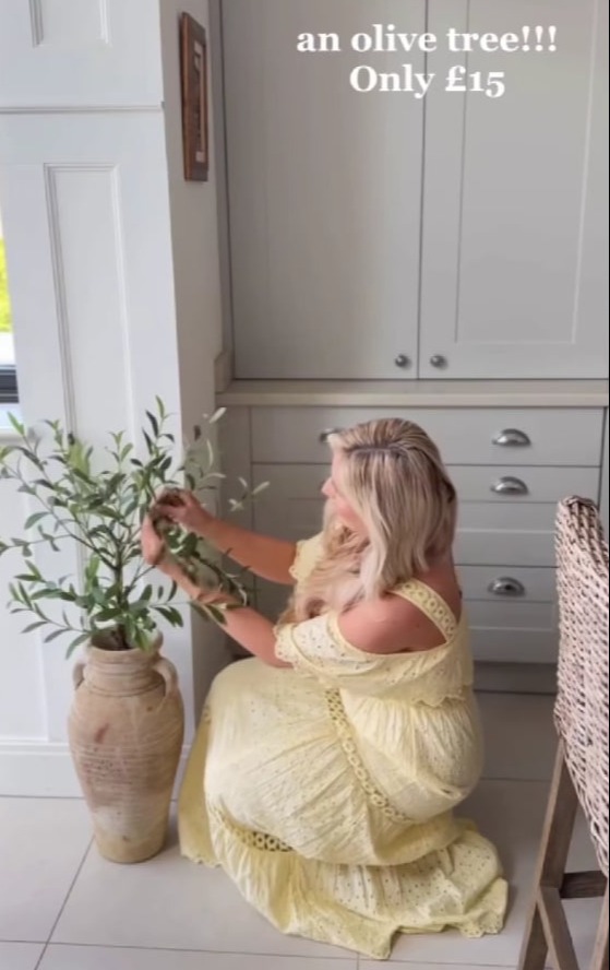 Woman arranging artificial olive tree in a vase.