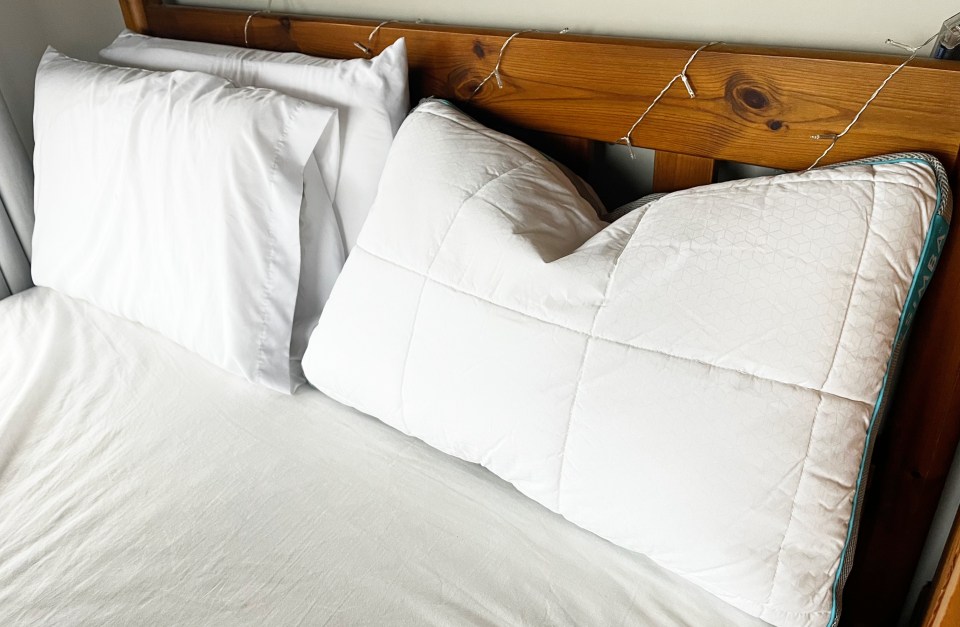 White pillows on a bed with string lights on the headboard.