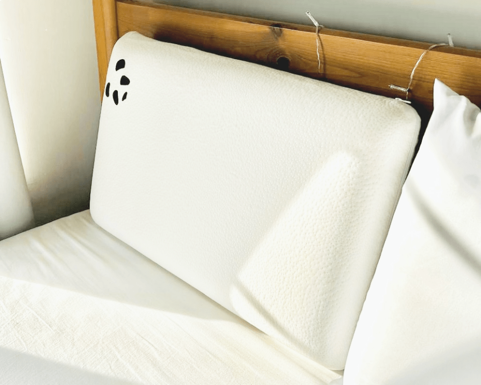White pillow with black panda-like design on a bed.