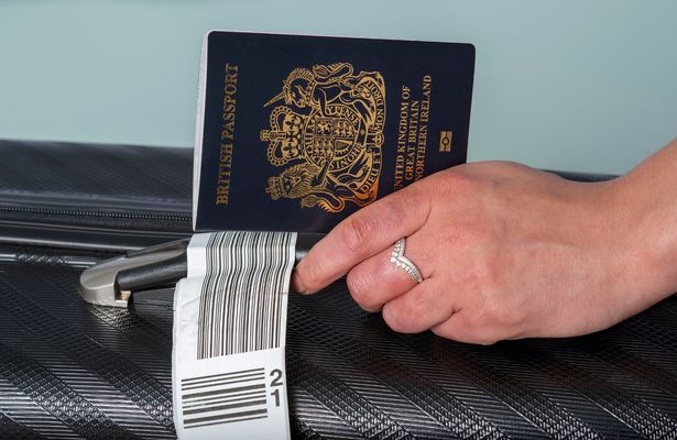 A man holding a blue British passport