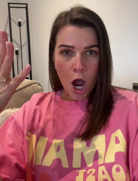 Woman in pink sweatshirt reacting with surprise.
