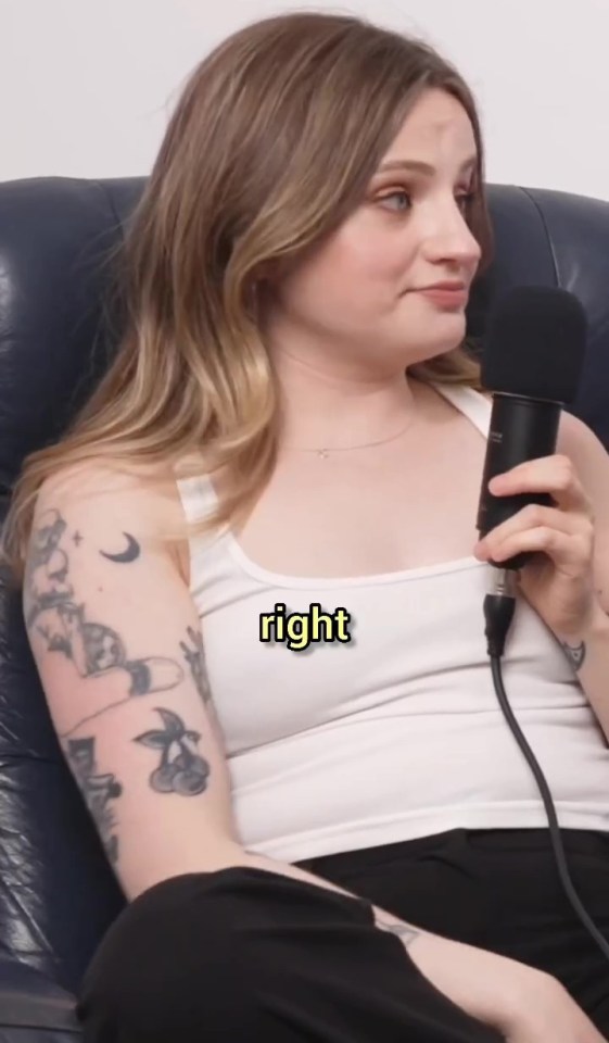 Woman with tattoos speaking into a microphone.