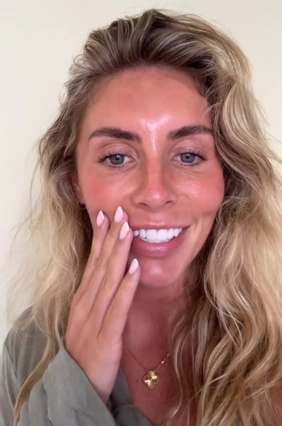 Woman smiling and touching her face.