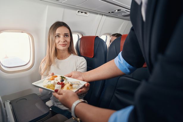 Image of woman being served inflight meal on plane
