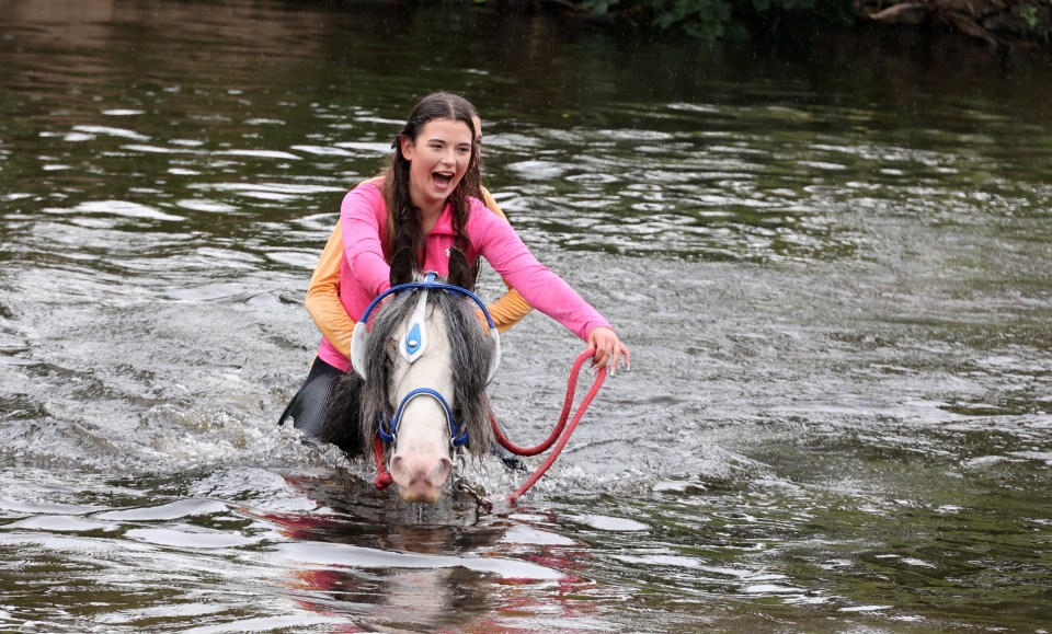 Girl riding horse through water at Appleby Horse Fair.
