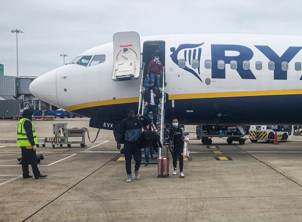 Passengers wearing masks disembarking a Ryanair plane at an airport.