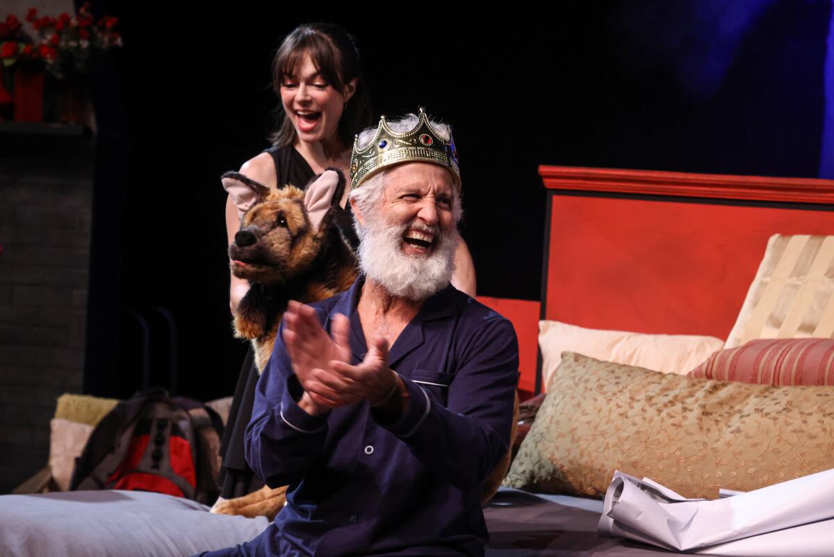 A man wearing a crown claps and laughs.
