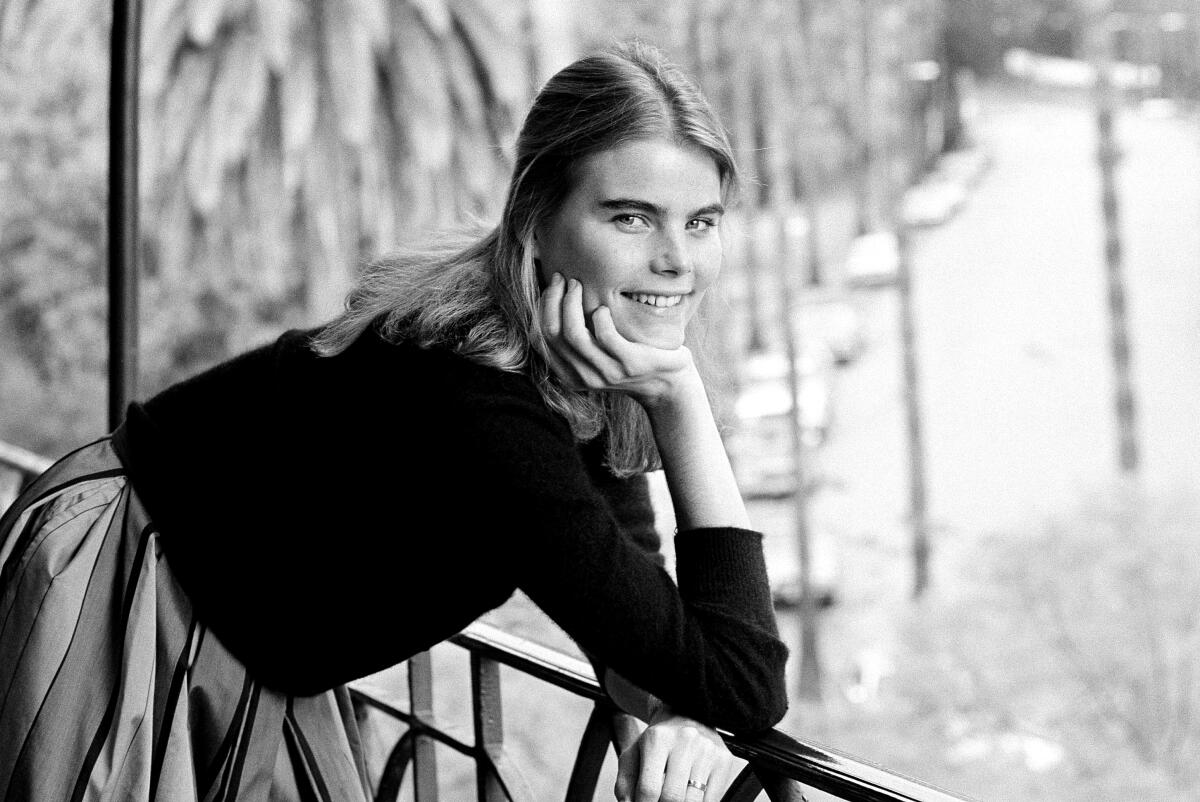 A smiling young actor poses on a balcony.