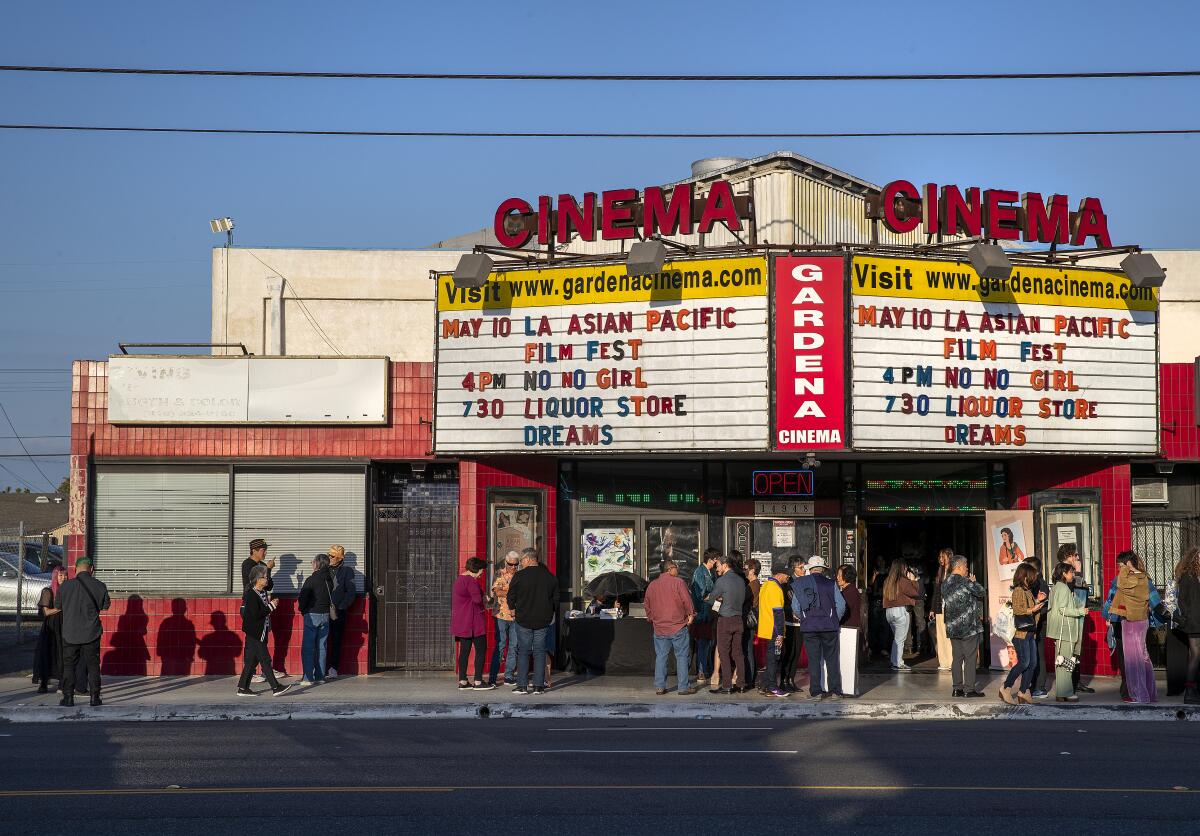 People gather outside a theater's marquee.