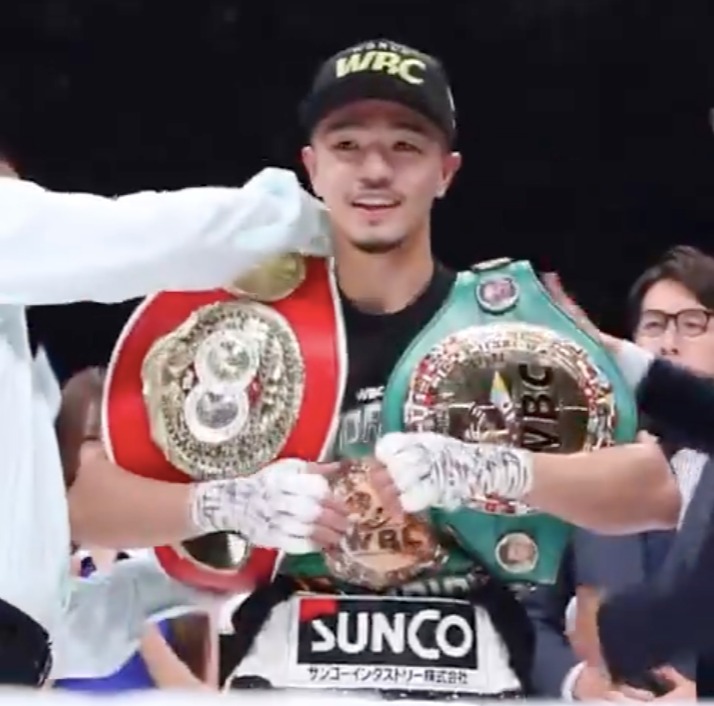 Boxer holding two championship belts.