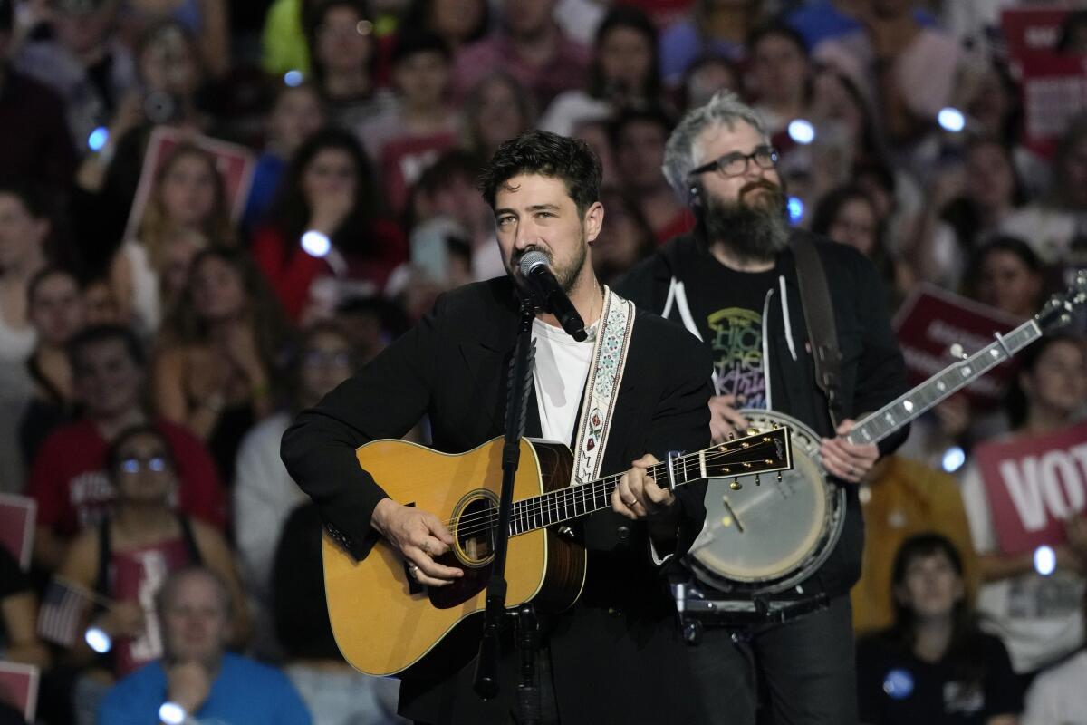 A guitarist and a banjo player perform before a large crowd.