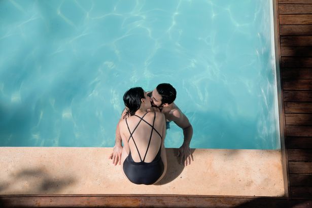 A picture of a couple kissing in a pool