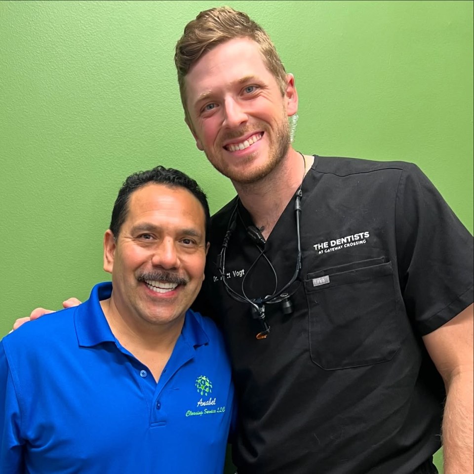 Photo of two men, one in a blue polo shirt and the other in a black scrub top.