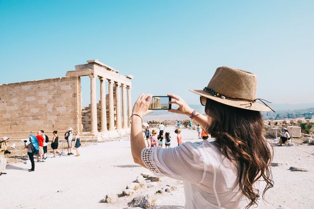 A woman takes a photo of the Acropolis in Athens