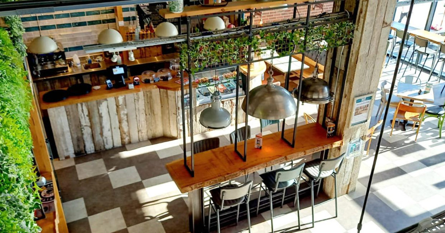 Industrial-chic bar interior with wooden bar, checkered floor, and hanging lights.