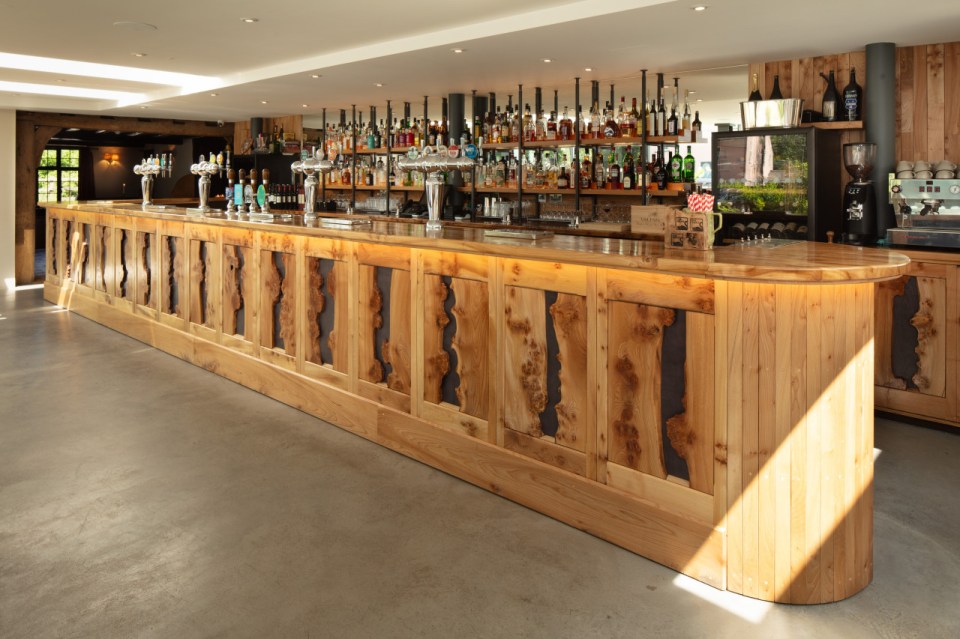 Long wooden bar with liquor shelves and taps.