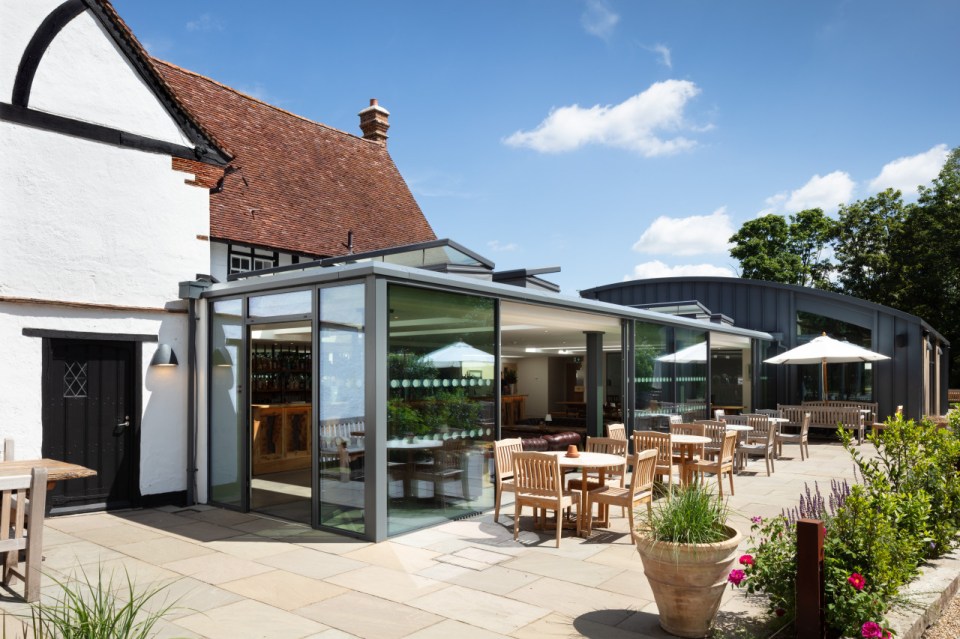 Outdoor patio area of a pub with a modern glass extension and traditional building.