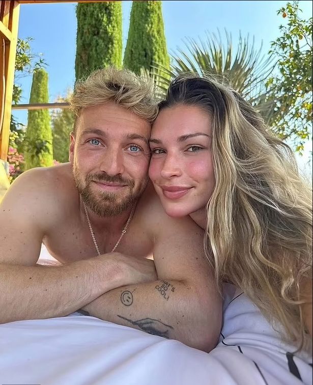 Sam Thompson and Zara McDermott take a selfie on holiday before their split. Sam is topless and their are palm trees in the background