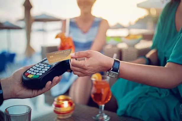 Girlfriends are paying their cocktails on the beach bar using contactless credit card