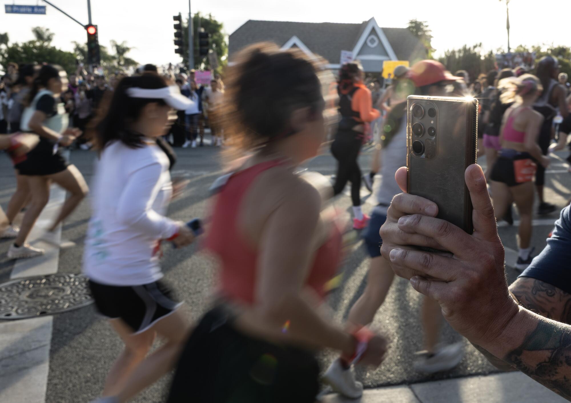 Supporters record and cheer as runners embark on the Nike women's half-marathon at the SoFi Stadium in Inglewood.