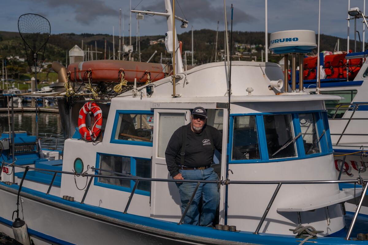 A man standing on a blue and white boat.
