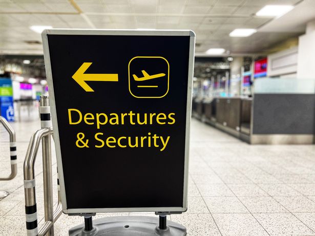 Close up of a sign directing passengers towards the departures and security area inside the airport terminal building.