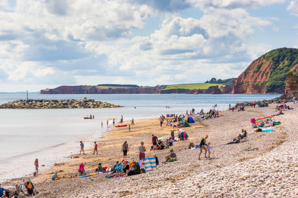 Families sunbathing and swimming on a beach.