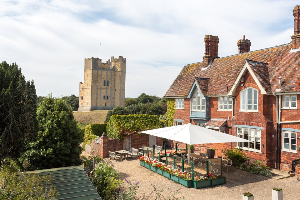 A brick building with a patio and a castle tower in the background.