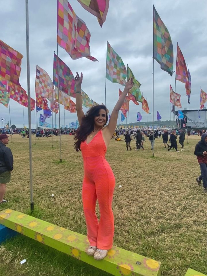 Woman in orange jumpsuit at a festival with colorful flags.