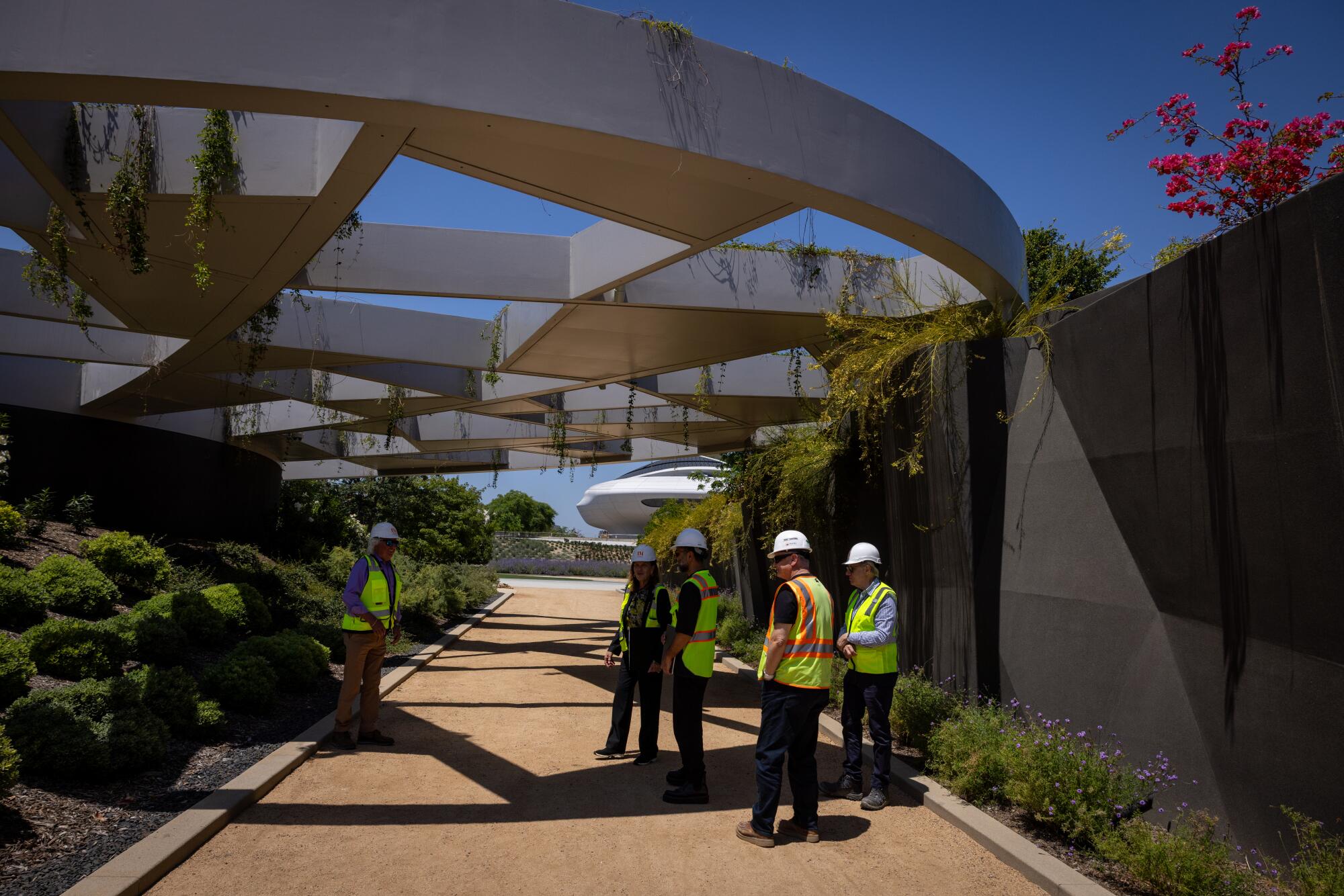 People stand under a massive, modernist trellis on the grounds of the Lucas Museum.
