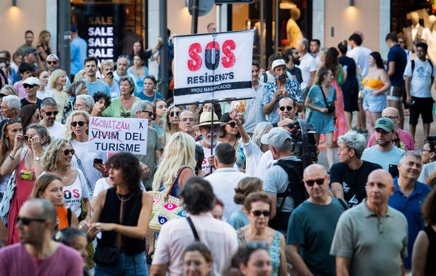 Protesters hold a banner which reads as "SOS Residents" as they take part in a demonstration against overtourism and housing prices on the island of Mallorca in Palma de Mallorca on July 21, 2024. (Photo by JAIME REINA / AFP) (Photo by JAIME REINA/AFP via Getty Images)