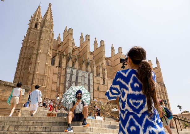 A tourist takes a picture in front of the cathedral of Palma de Mallorca on June 13, 2025. (Photo by JAIME REINA / AFP) (Photo by JAIME REINA/AFP via Getty Images)