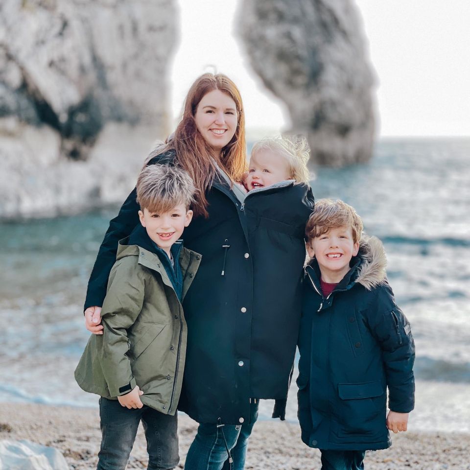 A mother and her three sons on a beach.