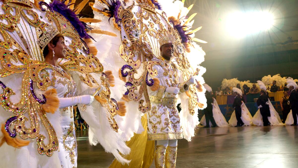 A man wearing an elaborate white and gold costume with a feather headdress